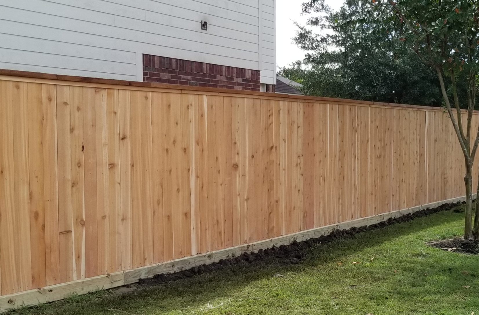 Cedar privacy fence with 2x6 pressure treated rot board, cedar pickets, 2x6 cedar top cap and 1x2 cedar trim.